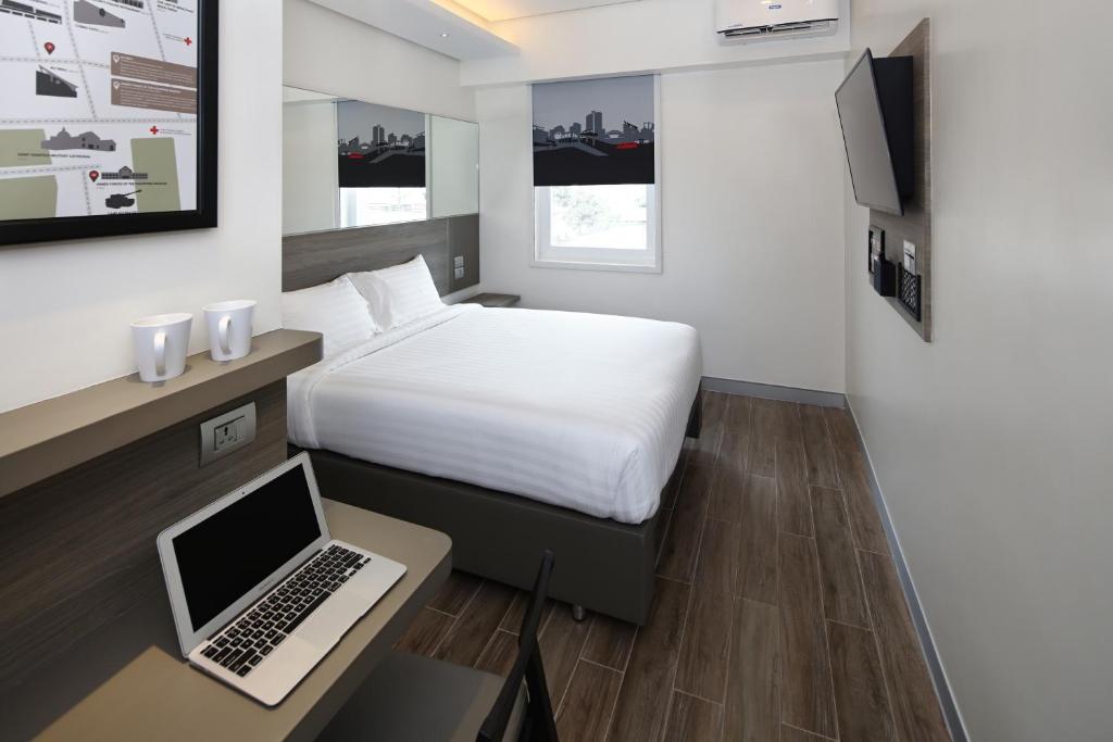 een slaapkamer met een bed en een laptop op een bureau bij Red Planet BGC The Fort in Manilla