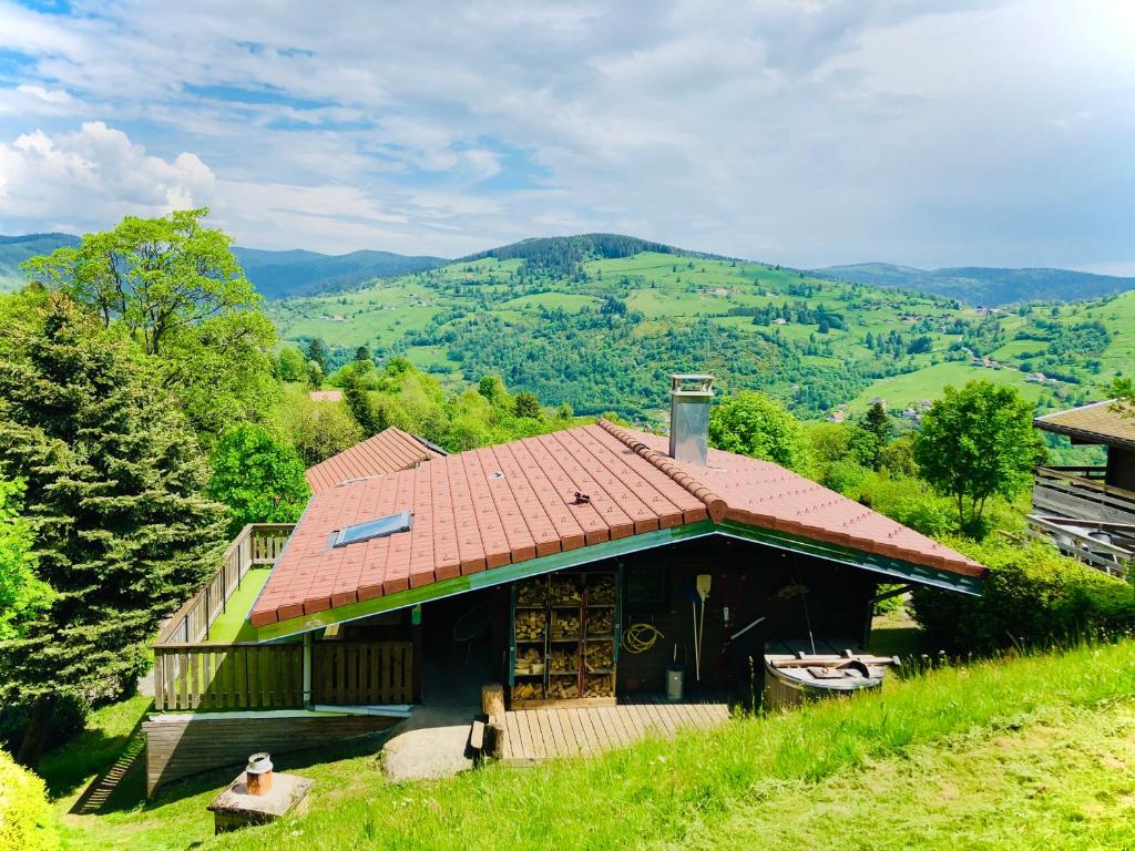 une maison avec un toit rouge sur une colline dans l'établissement Chalet Le Vintage, à La Bresse