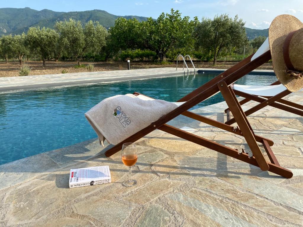 a glass of wine and a chair next to a swimming pool at Villa Eleonas by the Sea with private pool in Kainoúryion