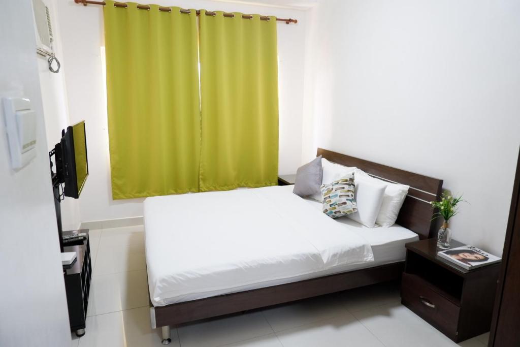 a bedroom with a bed with a green curtain at Tancor Residential Suites in Cebu City