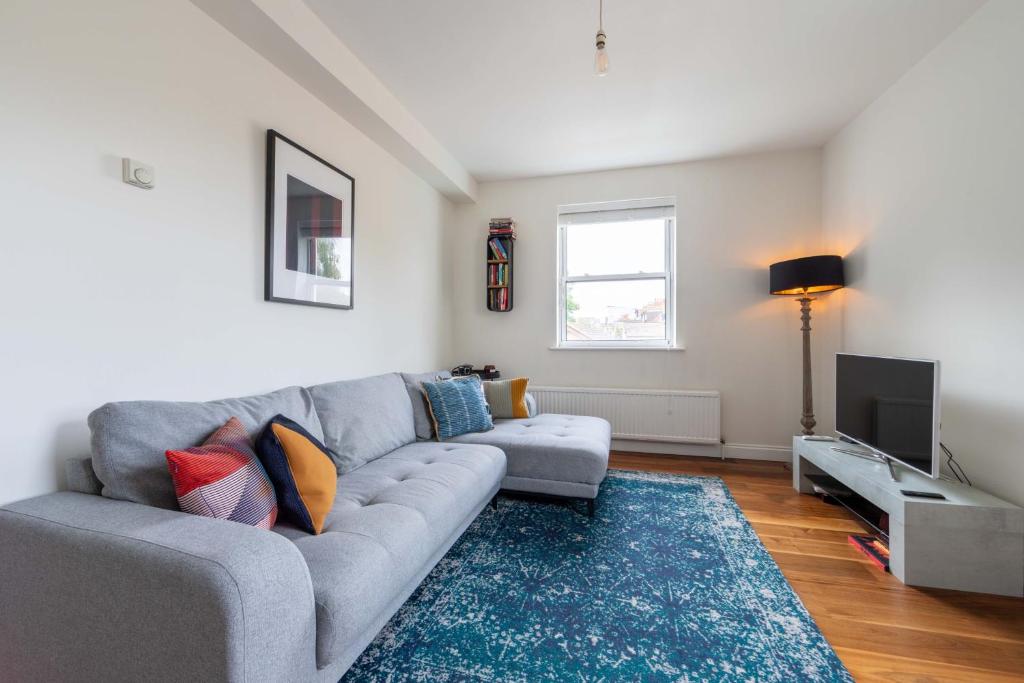 a living room with a gray couch and a television at Pass the Keys Bright Apartment in Peckham with Free Parking in London