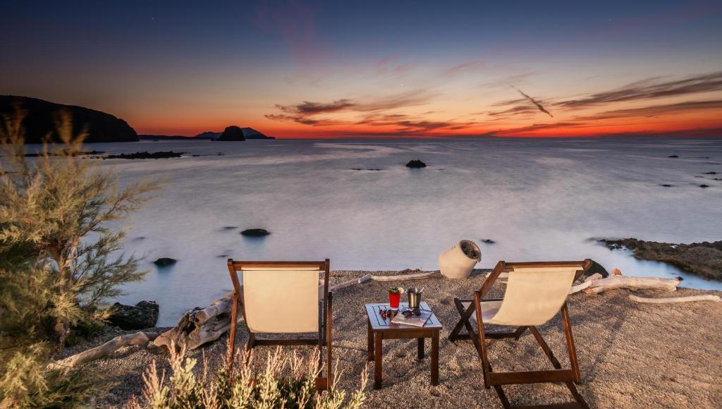 - deux chaises et une table sur la plage au coucher du soleil dans l'établissement Tania Milos, à Pollonia