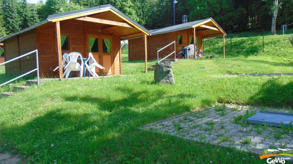 eine Holzhütte auf einem Feld mit einem Rasenplatz in der Unterkunft Blockhütte am Kegelsberg in Gelenau