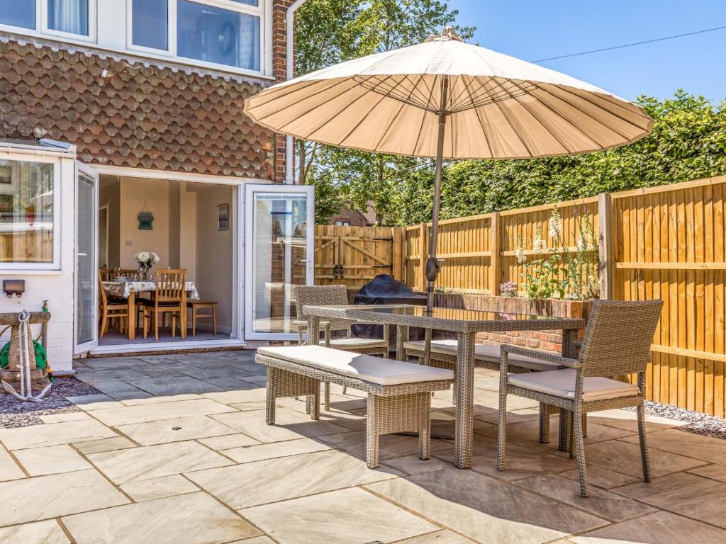 a patio with a table and an umbrella at Pass the Keys 3 bedroom Cottage in the heart of beautiful Bosham in Chichester