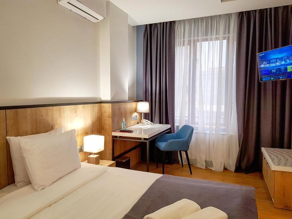 een hotelkamer met een bed, een bureau en een raam bij Hotel Alpha in Jerevan