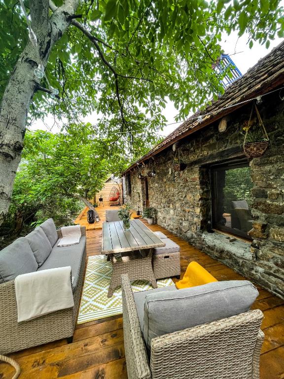 a patio with couches and a table and a stone building at The Hunter House in Ciudanoviţa