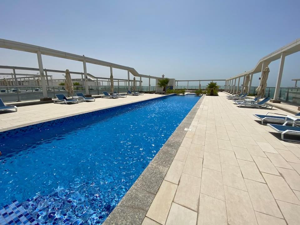 a swimming pool with lounge chairs on a building at Breathtaking Studio Apartment in Marjan Island in Ras al Khaimah