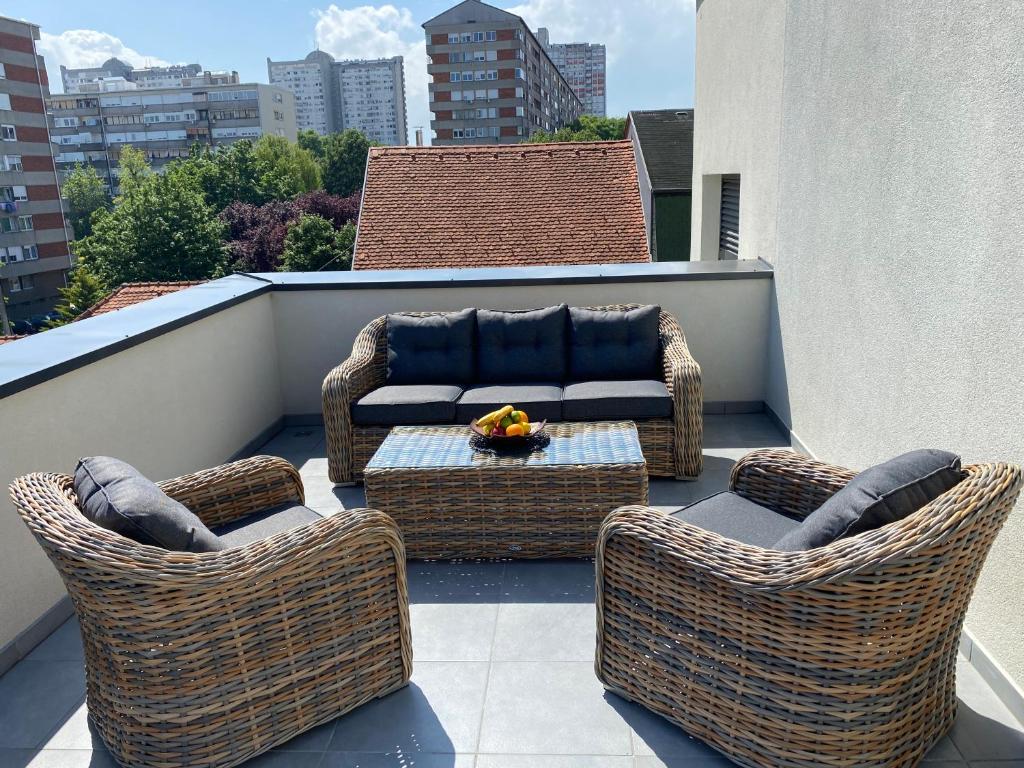 eine Terrasse mit Korbstühlen und einem Sofa auf dem Balkon in der Unterkunft 4-star Zagreb Penthouse in Zagreb