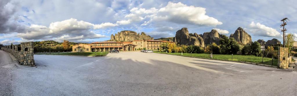 a building on a road with a mountain in the background at Grand Meteora Hotel in Kalabaka