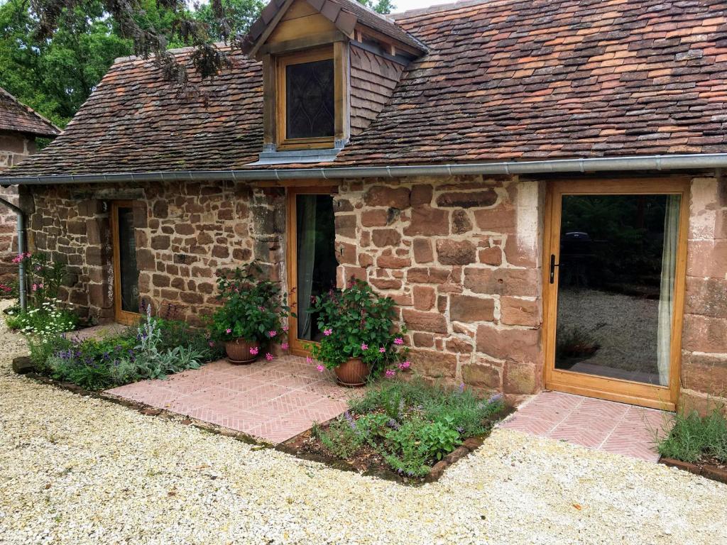 Boisseuilh的住宿－Countryside tiny house near Chateau de Hautefort，前面有盆栽植物的石头房子