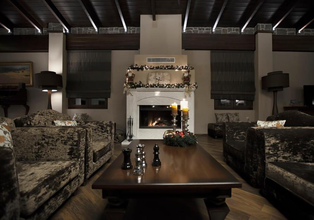 a living room with a fireplace with two couches and a table at Grand Meteora Hotel in Kalabaka