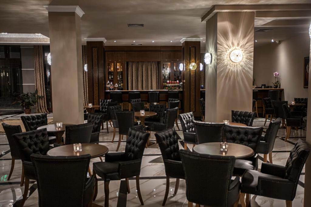 a restaurant with tables and chairs and a bar at Grand Meteora Hotel in Kalabaka