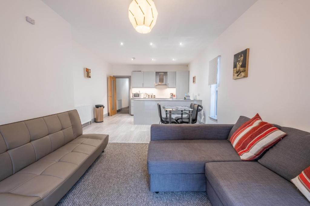 ein Wohnzimmer mit 2 Sofas und einer Küche in der Unterkunft Portrush Marine Apartments flat 3 in Portrush