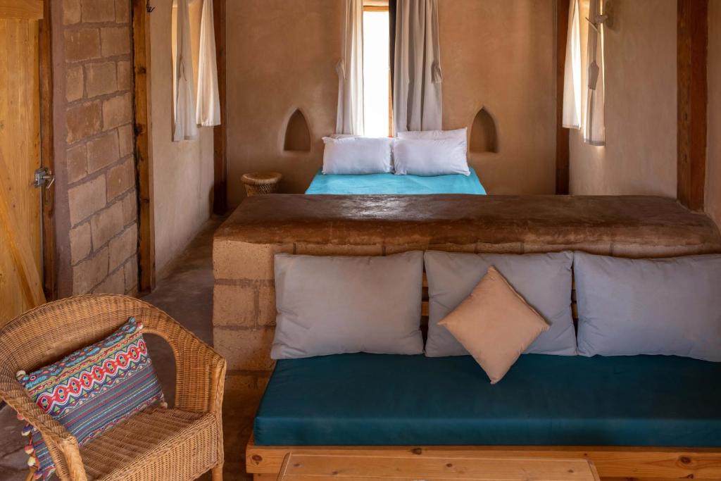 2 letti in una camera con divano e sedia di Desert Days mud cabin's Resort a Zuqim