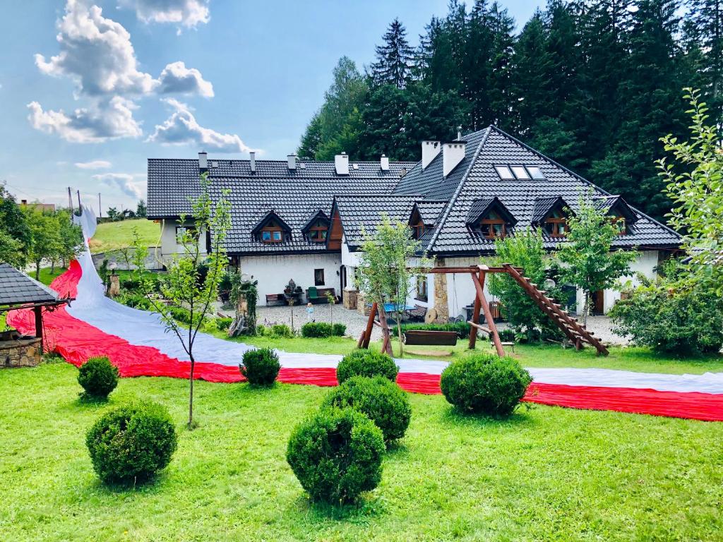 a house with a red carpet and a playground at Agroturystyka „Na Połomiu” in Istebna