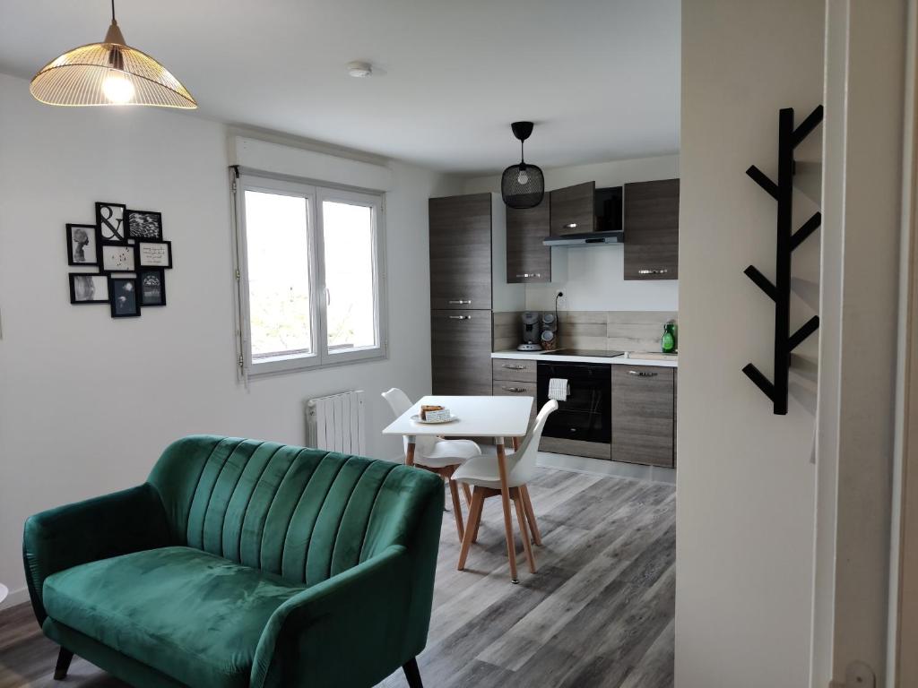 a living room with a green couch and a table at Calme et charmant T1 bis in Brest