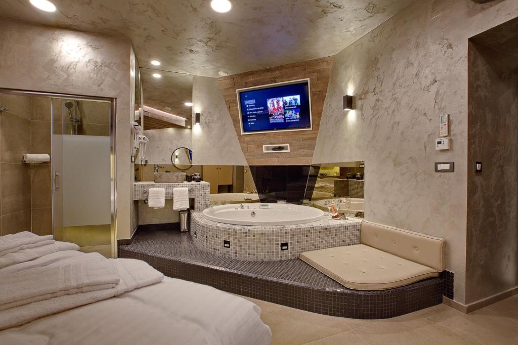 a bathroom with a tub and a tv on the wall at Bedroom more than a bed in Zagreb