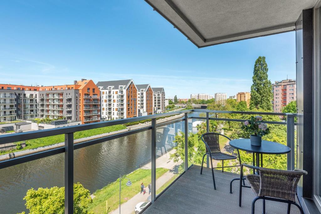 balkon ze stołem i krzesłami oraz widokiem na rzekę w obiekcie GRANO FLATS Gdańsk - RiverFront Apartment w Gdańsku