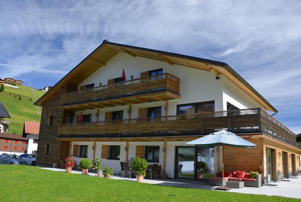 a large building with a balcony and an umbrella at Das Tannberg in Lech am Arlberg