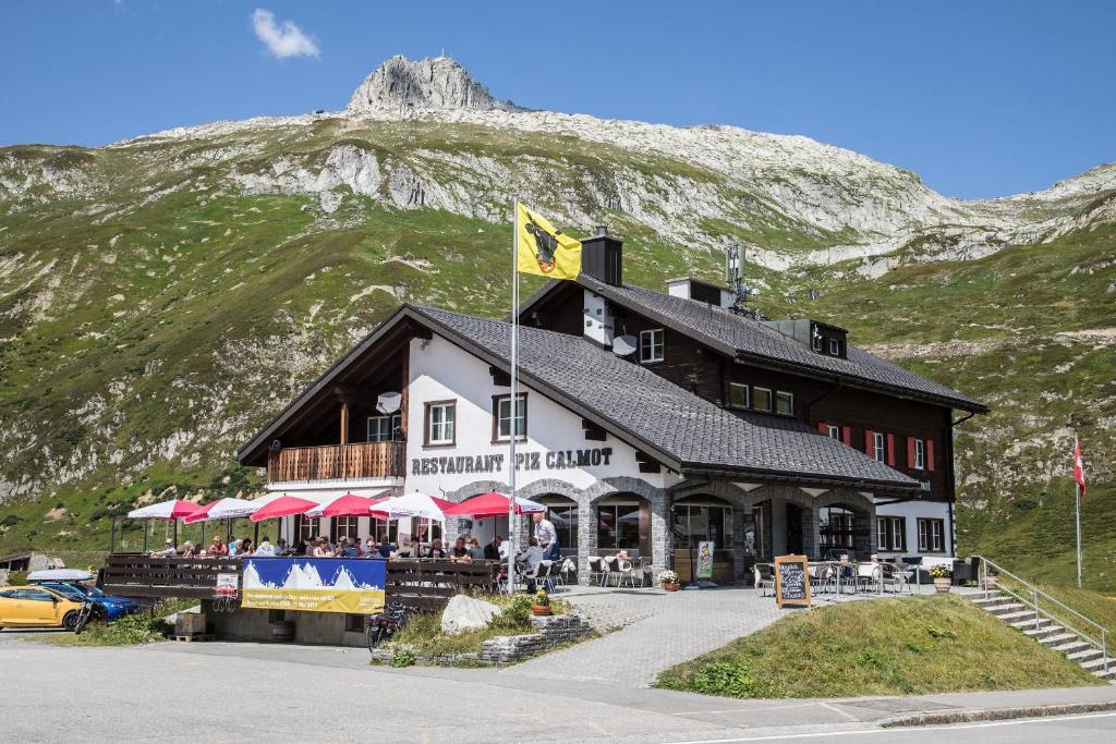 un grand bâtiment avec une montagne en arrière-plan dans l'établissement Berggasthaus Piz Calmot, à Andermatt