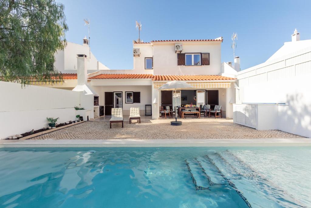 a villa with a swimming pool in front of a house at Vitamin Sea - Contemporary Beach Villa with heated pool in Altura