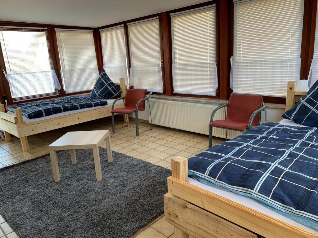 Zimmer mit 2 Betten, Stühlen und Fenstern in der Unterkunft Helene in Loxstedt