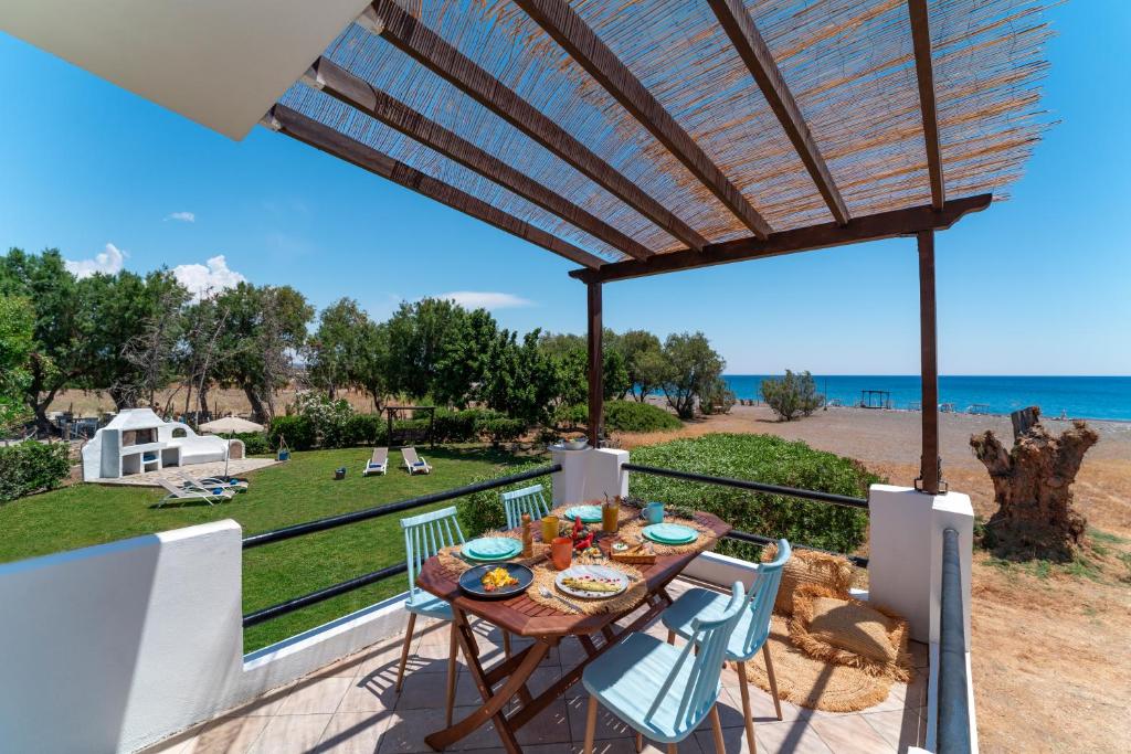 een patio met een tafel en stoelen en uitzicht op de oceaan bij Eco Beachfront Villa in Gennadi