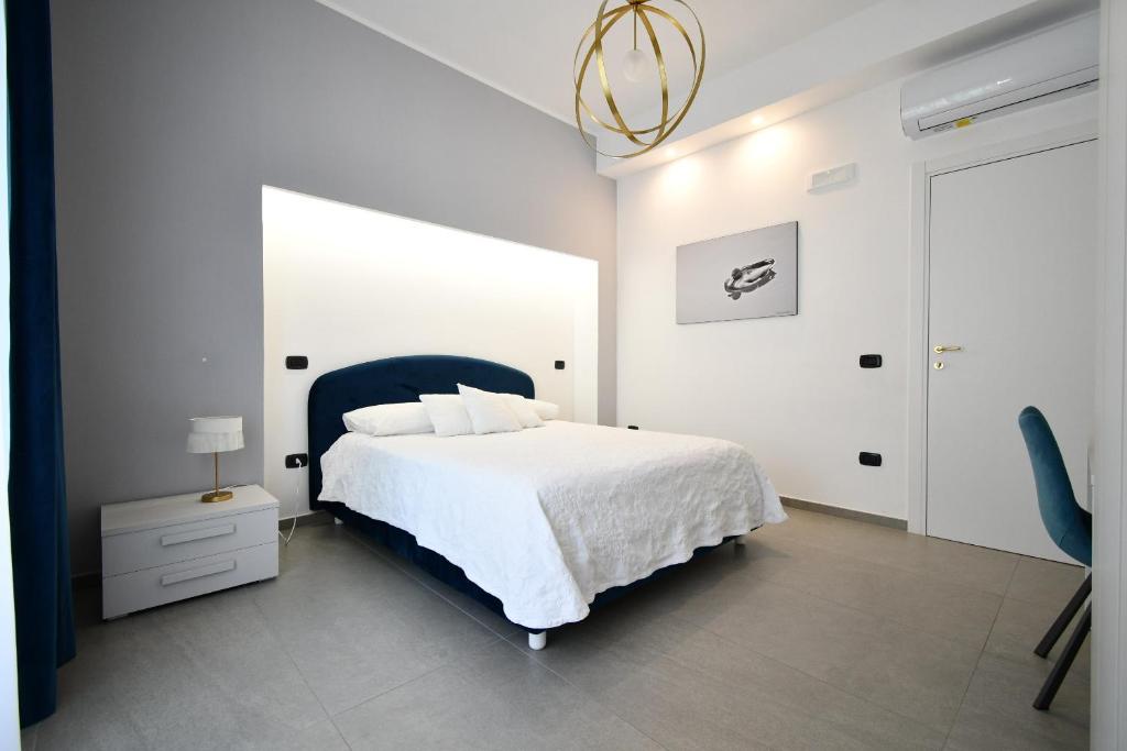 una camera bianca con un letto e una sedia di Maison Magò a Salerno