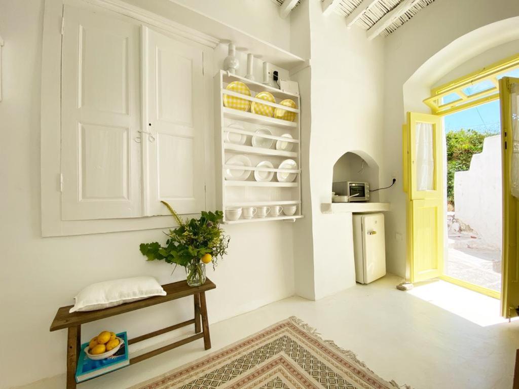 Serifos Lemon في سيريفوس شورا: مطبخ مع دواليب بيضاء وطاولة في الغرفة
