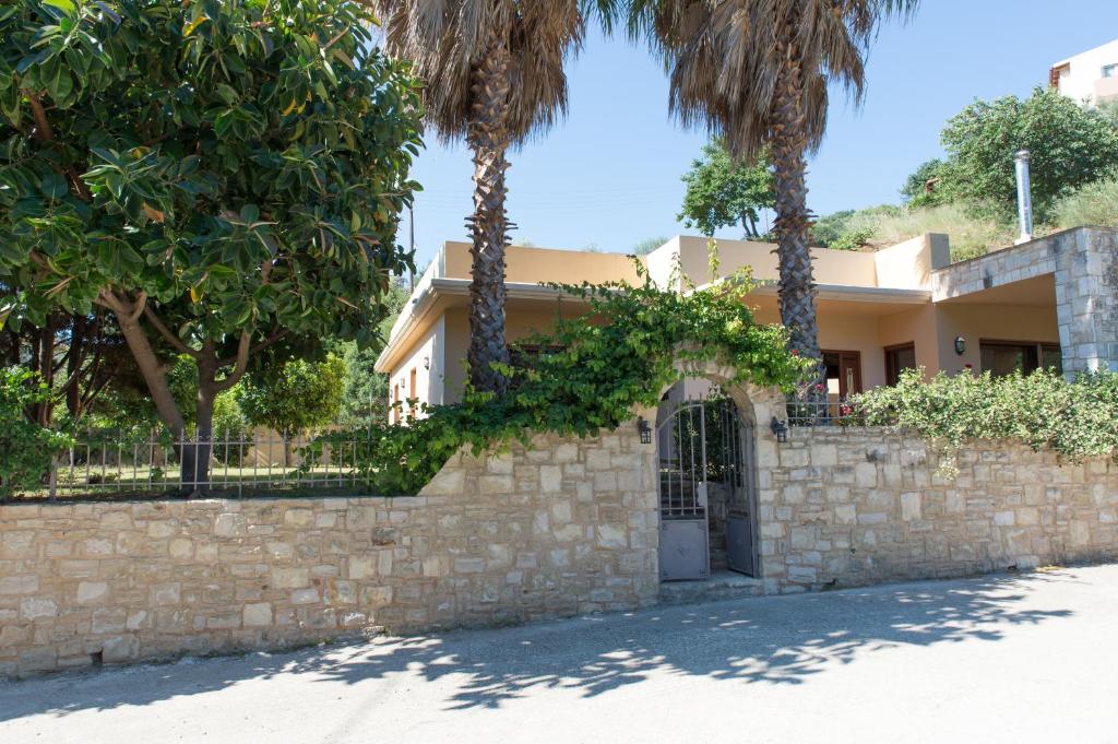 una casa con palmeras frente a una pared de piedra en Heraklion Comfy House with Mountain View, en Heraclión