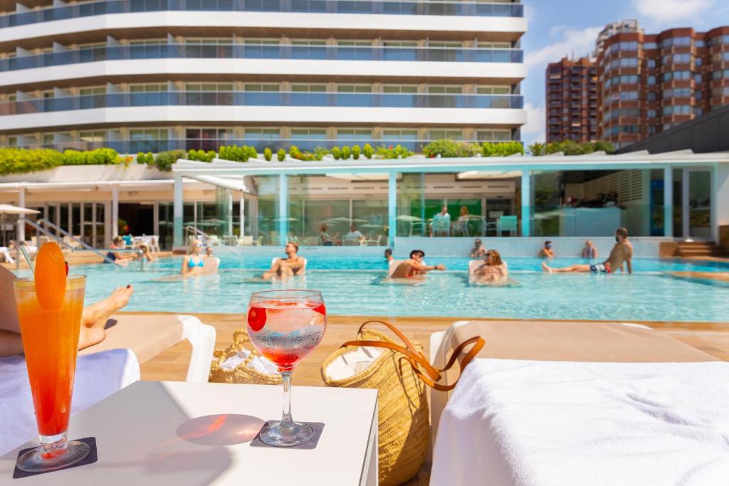 una mesa con una copa de vino frente a la piscina en Hotel Don Pancho - Designed for Adults en Benidorm