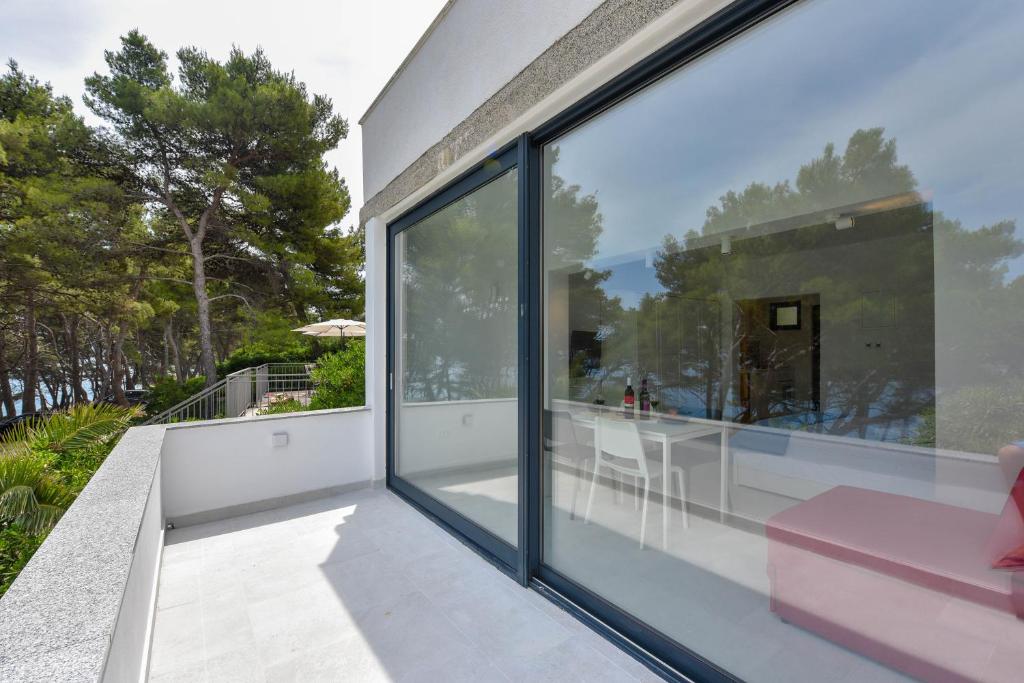 a balcony with large glass windows and a pink chair at Lazaneo Seafront Apartments, Jelsa Hvar in Jelsa