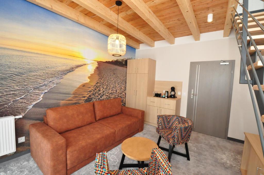 Bright lounge with beach sunset mural, brown sofa, colorful chairs, kitchenette cabinet and staircase.