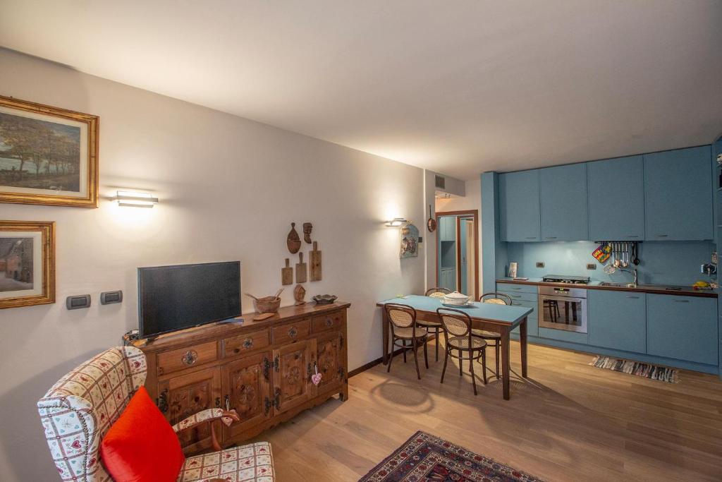 uma sala de estar com uma mesa e uma cozinha com armários azuis em L'Atelier du Temps - Joya Flat em Courmayeur
