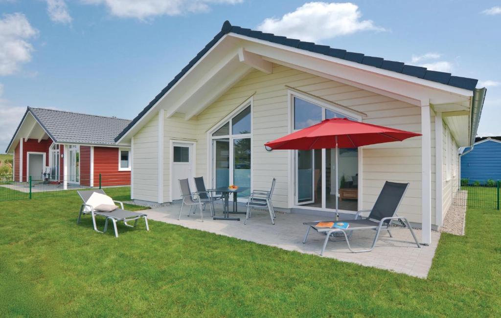 ein Haus mit einer Terrasse mit Stühlen und einem Sonnenschirm in der Unterkunft Awesome Home In Dagebll With 2 Bedrooms, Sauna And Wifi in Dagebüll