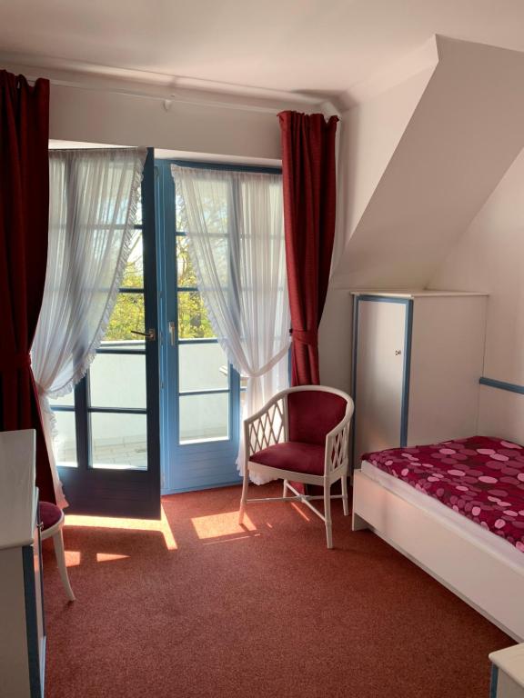 a bedroom with a bed and a chair and a window at Hotel Sundblick in Altefähr