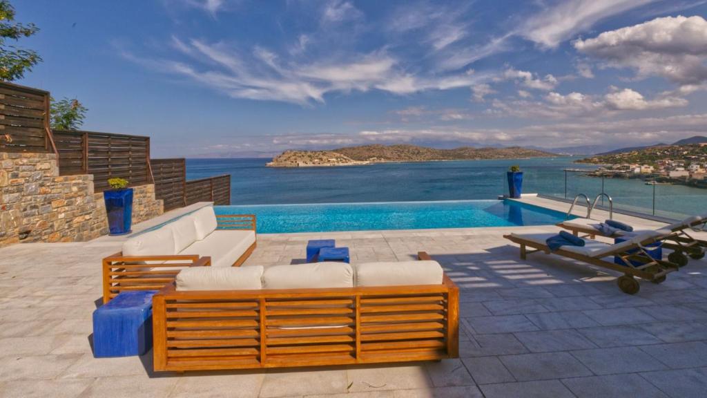 a pool with chairs and a view of the ocean at Luxury Villa Veronika in Pláka