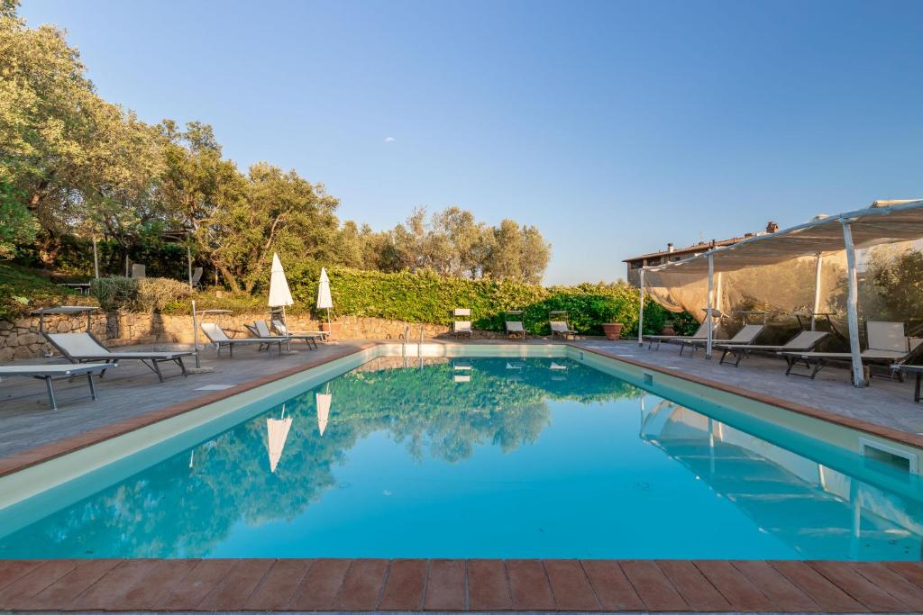 a swimming pool with chairs and umbrellas in a yard at La Casa Medioevale in Lamporecchio