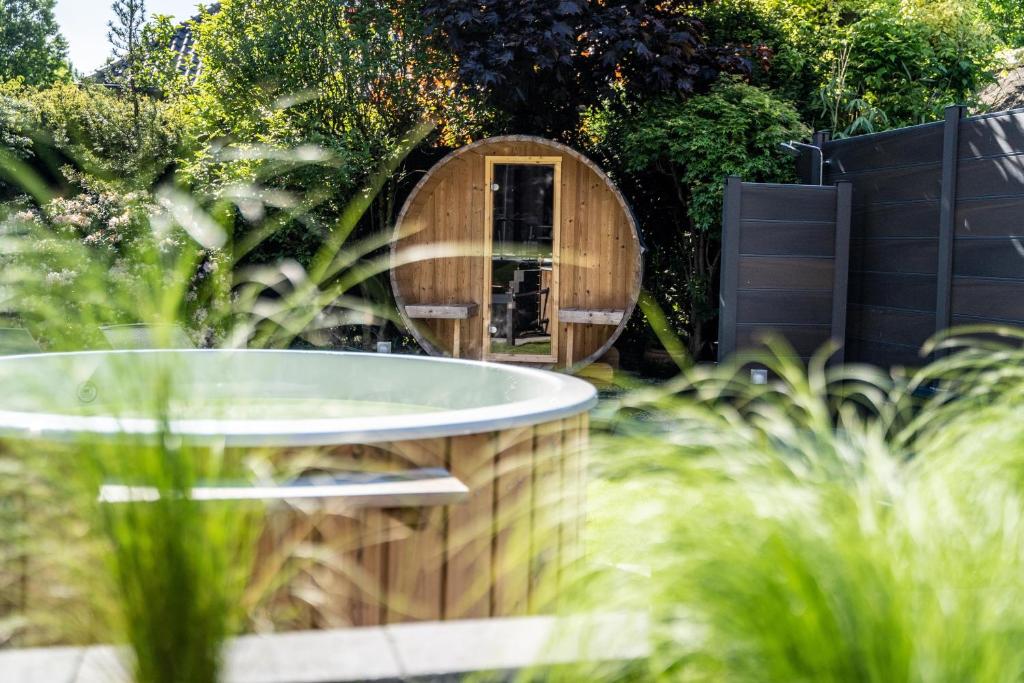 une baignoire en bois dans un jardin avec un miroir dans l'établissement hygge Niederrhein, à Rees