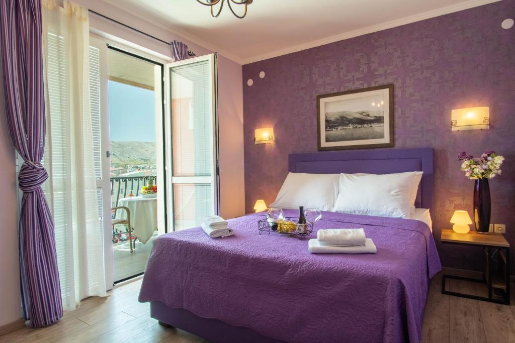 Dormitorio púrpura con cama y balcón en Rooms Villa Padre, en Pag