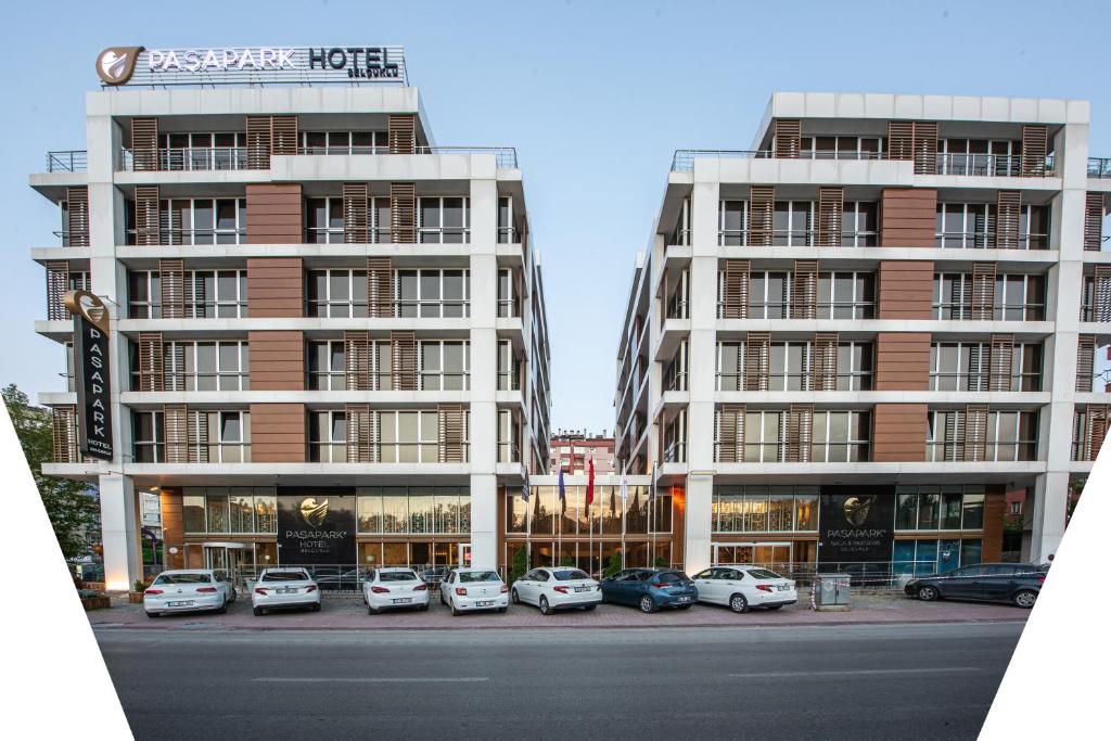 zwei hohe Gebäude mit Autos auf einem Parkplatz in der Unterkunft Paşapark Selçuklu Hotel in Konya