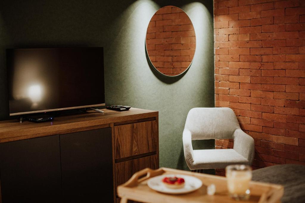 uma sala de estar com uma televisão e uma cadeira em Luxury inn em Tbilisi