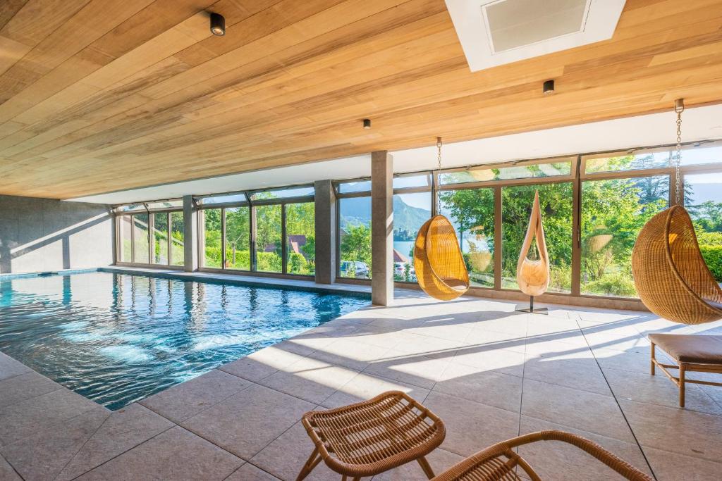 a swimming pool in a house with wooden ceilings at Hôtel Beau Site Talloires B SPA in Talloires