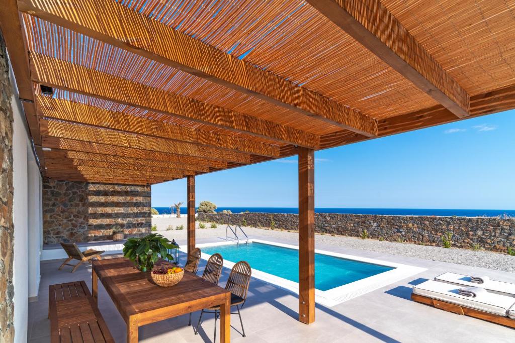 a patio with a wooden pergola and a swimming pool at Terra d'Oro Sea view villa with private pool in Kiotari