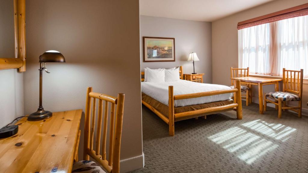 a bedroom with a bed and a table and a desk at Best Western Plus Plaza Hotel in Thermopolis