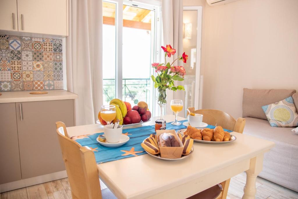 Nausika Cottage Corfu في باليوكاستريتسا: طاولة طعام عليها فاكهة ومشروبات