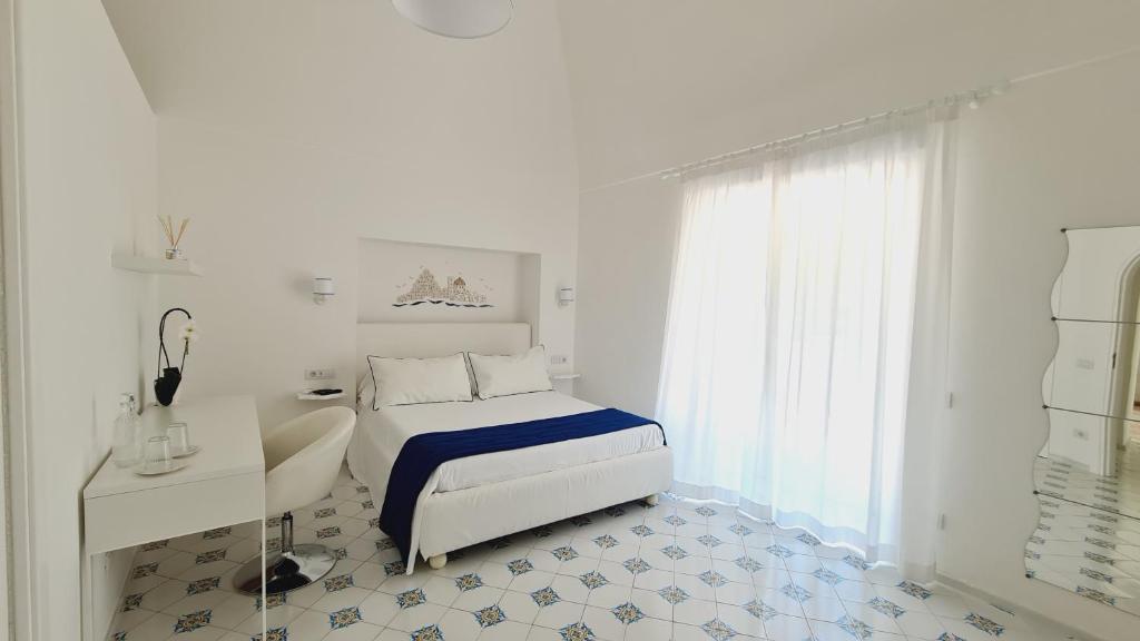 een witte slaapkamer met een bed en een bureau bij Casa Mandara B&B in Positano