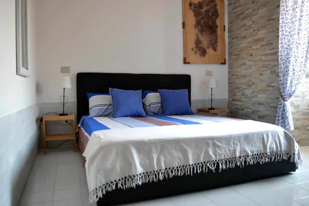 a bedroom with a large bed with blue pillows at Via Marina 19 - Casa sul mare. in Buggerru
