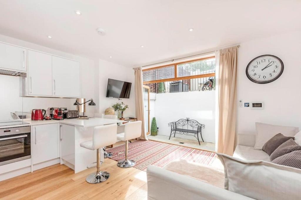 eine Küche und ein Wohnzimmer mit einer Uhr an der Wand in der Unterkunft 2 bed garden flat with air con by Fulham Broadway in London