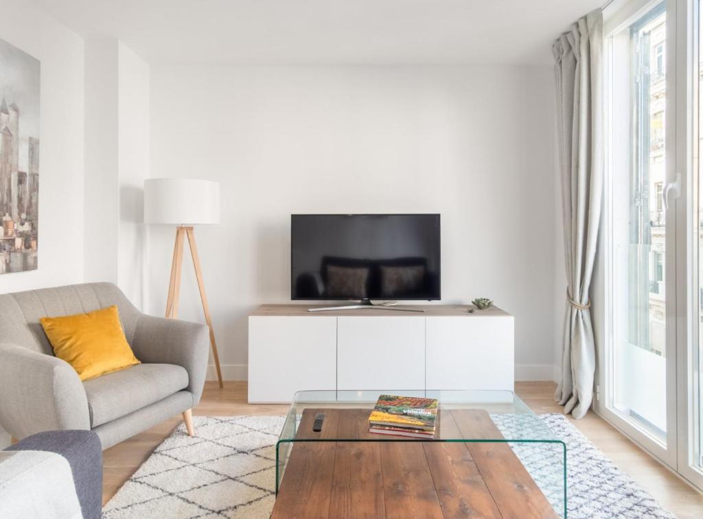 salon z kanapą i telewizorem w obiekcie Charming 1-Bedroom Apartment in Central Madrid Stylish Retreat for 2, Alonso Martinez I w Madrycie
